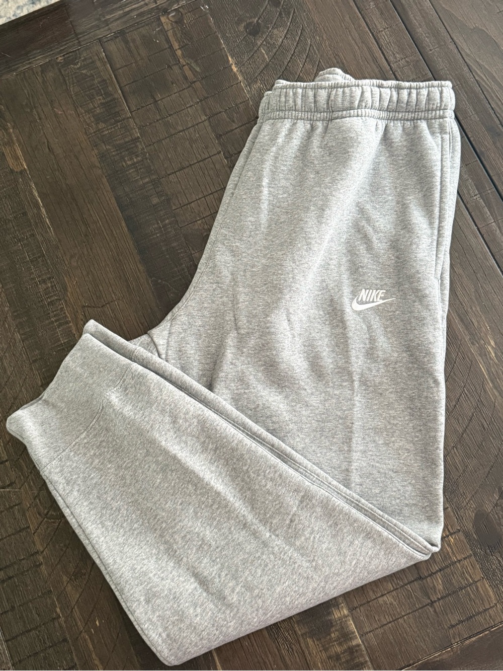 NWT gray Nike Sportswear Club Fleece joggers featuring an elastic waistband.